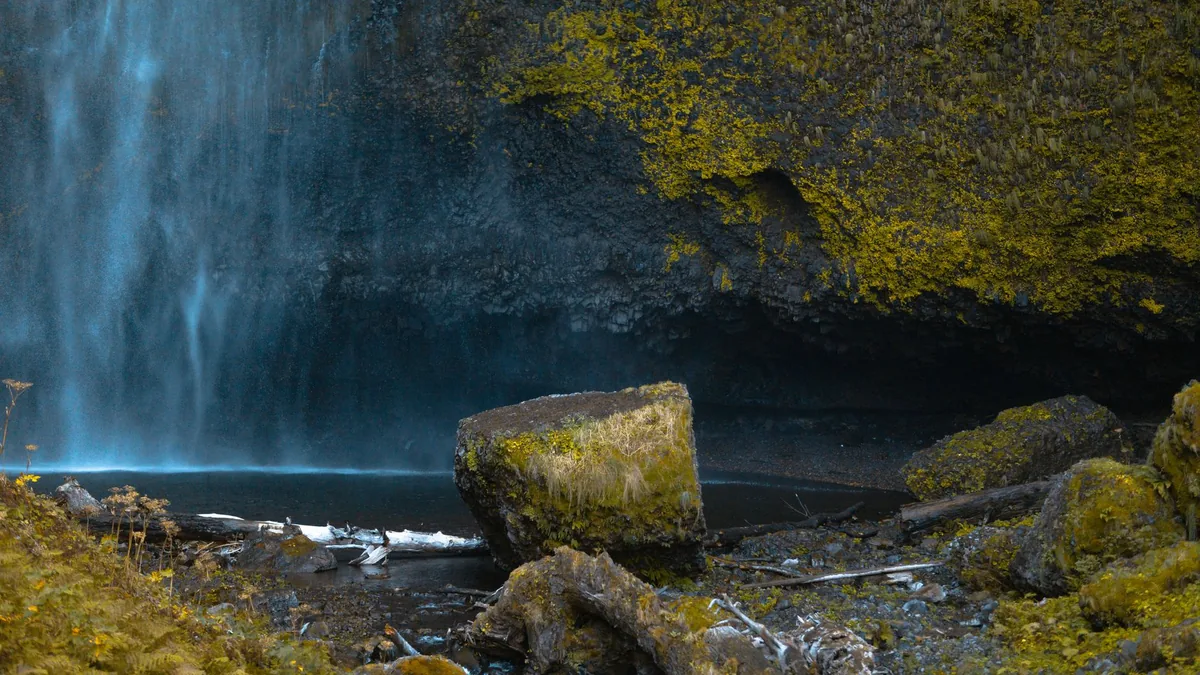 Serene waterfall cascading over moss-covered rocks in a tranquil outdoor setting.